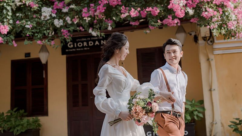 cô dâu tay cầm bó hoa cùng chú rể